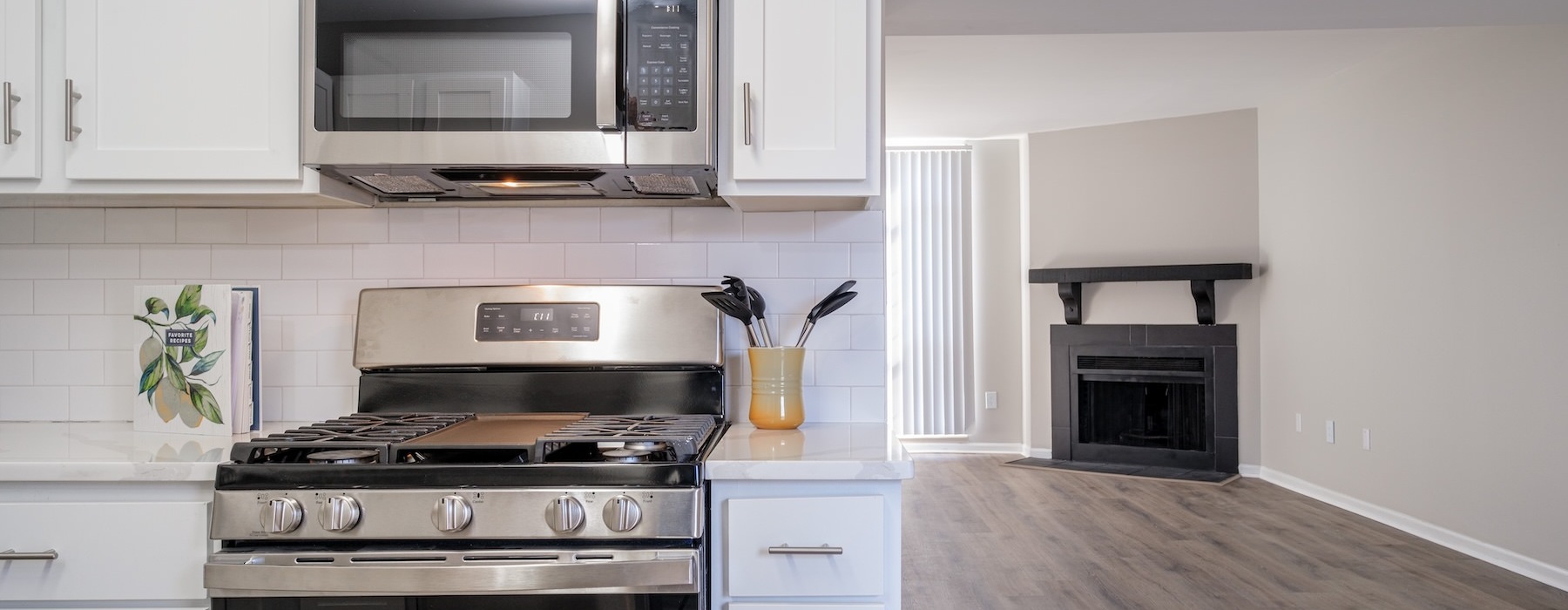 a kitchen with white cabinets and wood floors